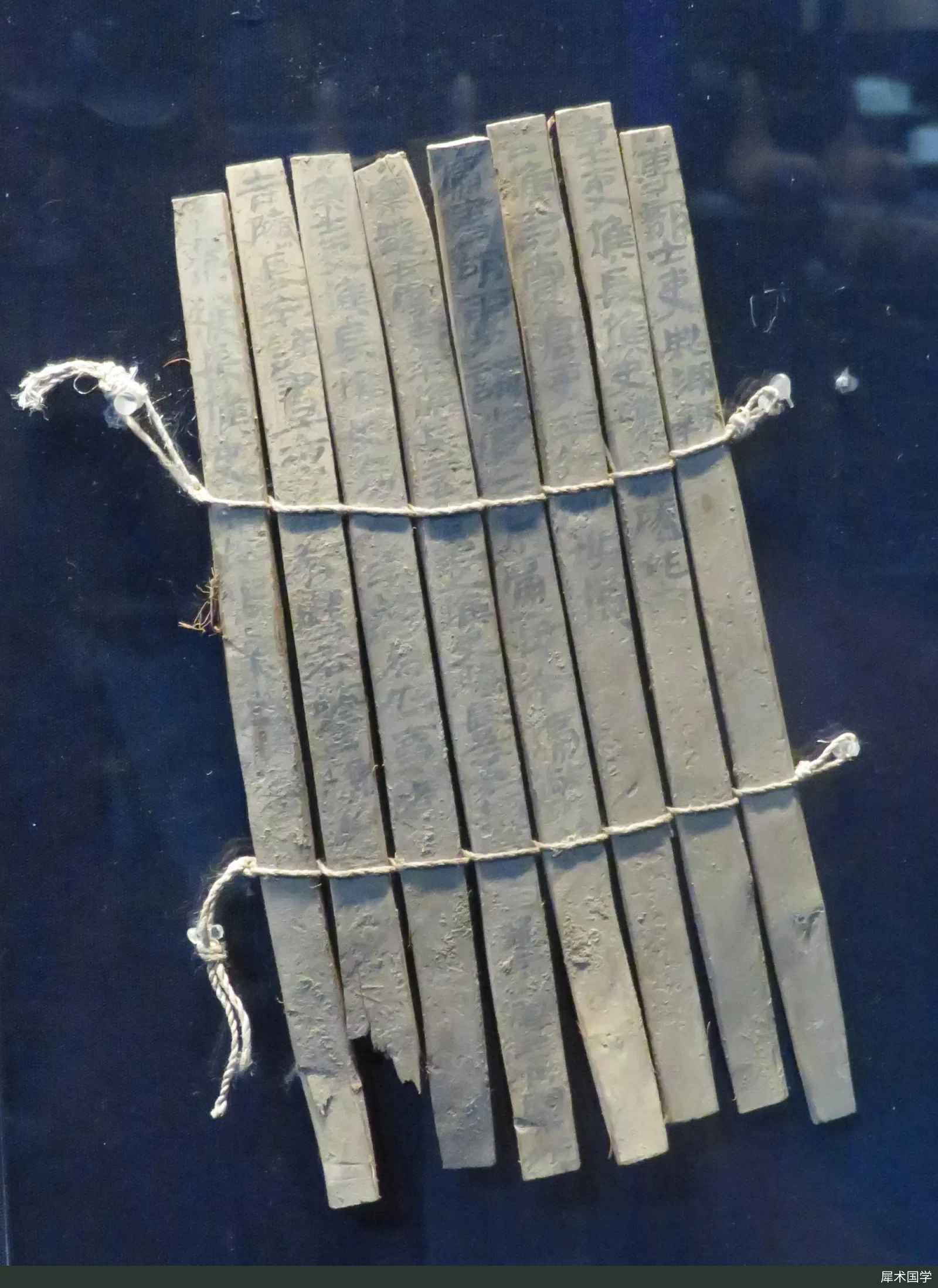 A group of Han-dynasty Juyan slips displayed at the Inner Mongolia Museum: several long, narrow slips lie side by side, with ink writing in clerical script visible on their surfaces